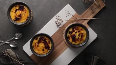 Creme brulee. Üzerinde karamelli şeker, kaşıklar, koyu kırsal masa olan Fransız vanilyalı tatlı kaseleri..
