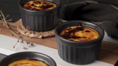 Creme brulee. Üzerinde karamelli şeker, kaşıklar, koyu kırsal masa olan Fransız vanilyalı tatlı kaseleri..