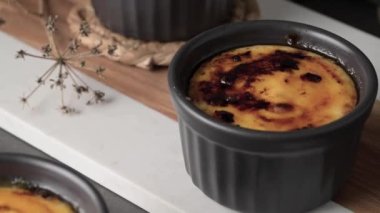 Creme brulee. Üzerinde karamelli şeker, kaşıklar, koyu kırsal masa olan Fransız vanilyalı tatlı kaseleri..