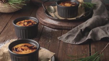 Creme brulee. Üzerinde karamelli şeker, kaşıklar, koyu kırsal masa olan Fransız vanilyalı tatlı kaseleri..