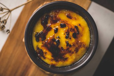 Creme brulee. Üzerinde karamelli şeker, kaşıklar, koyu kırsal masa olan Fransız vanilyalı tatlı kaseleri..