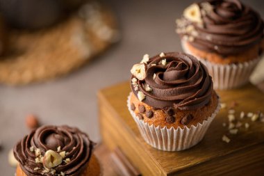 Çikolata parçalı çörekler, çikolatalı ganache ve fındıkla süslenmiş, klasik, siyah mutfak tezgahında..