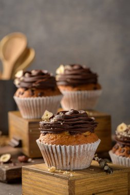 Çikolata parçalı çörekler, çikolatalı ganache ve fındıkla süslenmiş, klasik, siyah mutfak tezgahında..