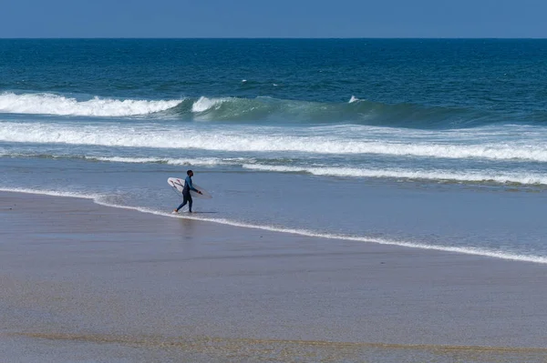 ポルトガルのFuradouro Beachの海に歩いてください 海で波を引く男たち サーフィンアクションウォーターボードスポーツ 人々は夏休みにスポーツレッスンやビーチスイミング活動をしています — ストック写真