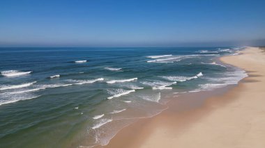 Kumlu sahil antenine çarpan dalgaların yan görüntüsü. Yukarıdan gelen boş bir sahile çarpan okyanus dalgalarının kuş bakışı görüntüsü..