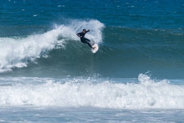 Portekiz, Furadouro Sahili 'nde sörf yapan bir sörfçü. Okyanusta dalgaları yakalayan adamlar. Su sörfü sporu. İnsanlar yaz tatilinde su sporları dersleri ve plaj yüzme aktiviteleri yapar..