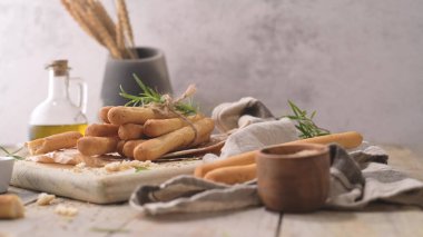 Traditional italian breadsticks grissini with rosemary, olive oil and sesame seeds on wooden countertop.