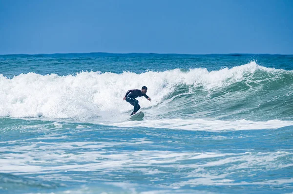 ポルトガルのFuradouro Beachで波に乗ってください 海で波を引く男たち サーフィンアクションウォーターボードスポーツ 人々は夏休みにスポーツレッスンやビーチスイミング活動をしています — ストック写真