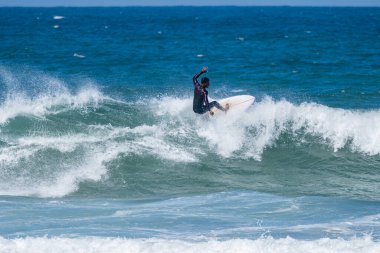 Portekiz, Furadouro Sahili 'nde sörf yapan bir sörfçü. Okyanusta dalgaları yakalayan adamlar. Su sörfü sporu. İnsanlar yaz tatilinde su sporları dersleri ve plaj yüzme aktiviteleri yapar..