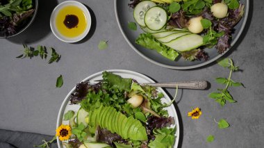 Fresh summer salad with cucumber, melon, avocado and fresh oregano served on ceramic plates.