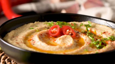 Seramik kasede nefis humus. Siyah ahşap arka planda renkli abur cubur kompozisyonu.