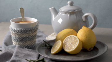 Örme sıcak kış eşarp ahşap masa üzerinde fincan limon ile çay giymiş.