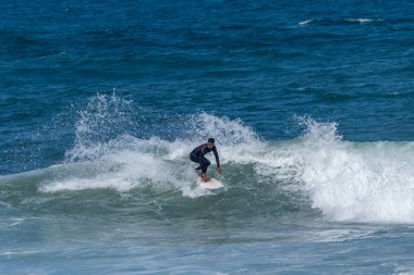 Portekiz, Furadouro Sahili 'nde sörf yapan bir sörfçü. Okyanusta dalgaları yakalayan adamlar. Su sörfü sporu. İnsanlar yaz tatilinde su sporları dersleri ve plaj yüzme aktiviteleri yapar..