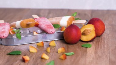Ev yapımı Ahududu ve ahşap bir masa üzerinde şeftali popsicles.