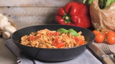 Ton balığı ve fesleğen ile İtalyan makarna. Eski ahşap arka plan üzerinde ton balığı ve domates soslu makarna.