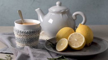Örme sıcak kış eşarp ahşap masa üzerinde fincan limon ile çay giymiş.