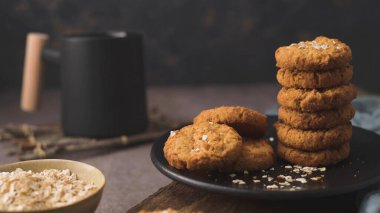 Homemade oatmeal raisin cookies with cup of cappuccino on rustic background.