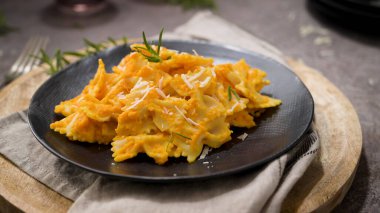 Koyu taştan mutfak tezgahında seramik tabakta kabak soslu Farfalle makarna..