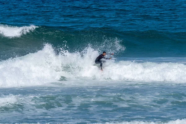 ポルトガルのFuradouro Beachで波に乗ってください 海で波を引く男たち サーフィンアクションウォーターボードスポーツ 人々は夏休みにスポーツレッスンやビーチスイミング活動をしています — ストック写真