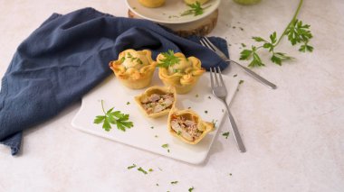 Tavuklu turtalar ve maydanoz yaprakları mutfak tezgahında beyaz seramik tabaklarda.