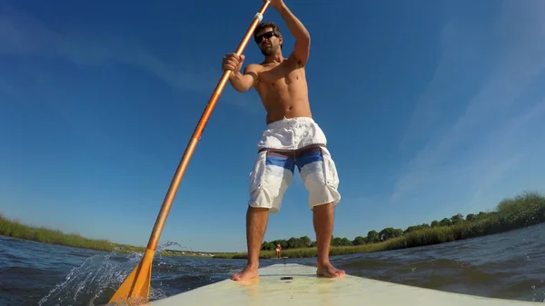 男は湖の Paddleboarding します 湖でウォーター スポーツをしている若い男 夏休み水着で男性の観光客 — ストック写真