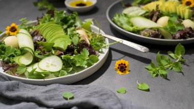 Seramik tabakta servis edilen salatalık, kavun, avokado ve taze kekik taze yaz salatası..