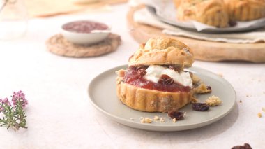 Çilek reçelli çörekler ve beyaz mutfak tezgahında cam şişede servis edilen sütlü pıhtılaşmış krema..