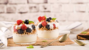 Granola böğürtlen ve ahududu. Açık beyaz ahşap arka planda ev yapımı yoğurt. Sağlıklı gıda konsepti.