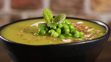 Green pea soup with linseed and pumpkin and sunflower seeds on a rustic kitchen countertop. clipart