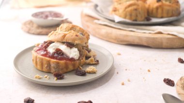 Çilek reçelli çörekler ve beyaz mutfak tezgahında cam şişede servis edilen sütlü pıhtılaşmış krema..