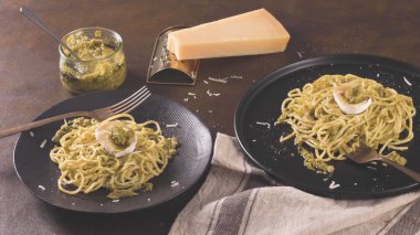 Karanlık mutfak tezgahında fesleğen soslu ve peynirli taze spagetti..