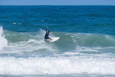 Portekiz, Furadouro Sahili 'nde sörf yapan bir sörfçü. Okyanusta dalgaları yakalayan adamlar. Su sörfü sporu. İnsanlar yaz tatilinde su sporları dersleri ve plaj yüzme aktiviteleri yapar..