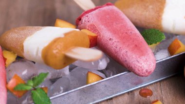 Ev yapımı Ahududu ve ahşap bir masa üzerinde şeftali popsicles.