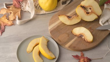 Olgun sarı ayvaları veya Kraliçe elma meyve ve zanaat mantar levha rustik siyah arka plan üzerine tohum ile dilimlenmiş Ayva tatlısı.