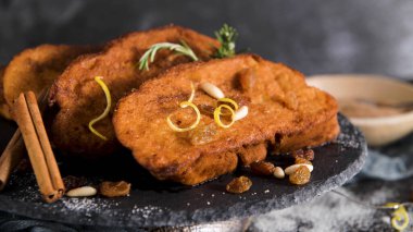 Traditional Christmas Rabanadas with lemon zest, raisins, pine nuts and cinnamon. Spanish Torrijas or french toasts close up on the countertop