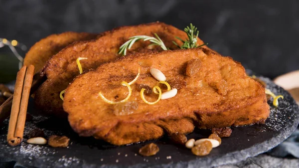 Traditional Christmas Rabanadas with lemon zest, raisins, pine nuts and cinnamon. Spanish Torrijas or french toasts close up on the countertop