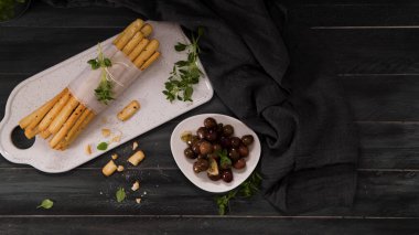 Taze pişmiş ev yapımı Grissini ekmek çubukları beyaz seramik tepside ve mutfak tezgahının üzerinde zeytinyağı ve fesleğen otu ile.