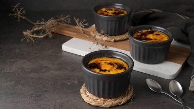 Creme brulee. Üzerinde karamelli şeker, kaşıklar, koyu kırsal masa olan Fransız vanilyalı tatlı kaseleri..