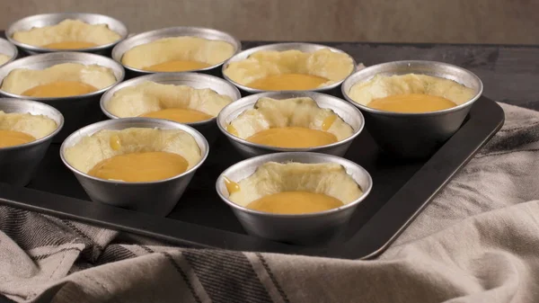 Egg tarts, traditional portuguese dessert, pastel de nata, custard tarts during home production on metal tray.