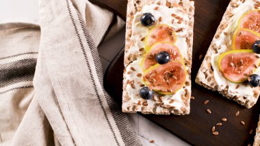 Kanepe veya crostini ile krem peynir ve taze incir dilimleri bir ahşap tahta üzerinde buğday crispread. Lezzetli meze bir aperatif ideal.