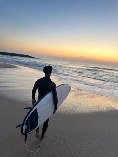 Surffari Kävelee Rannalla Aaltojen Kanssa Auringonlaskun Aikaan Portugalissa — kuvapankkivalokuva