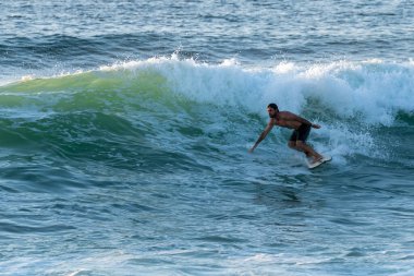 Portekiz, Furadouro Sahili 'nde sörf yapan bir sörfçü. Okyanusta dalgaları yakalayan adamlar. Su sörfü sporu. İnsanlar yaz tatilinde su sporları dersleri ve plaj yüzme aktiviteleri yapar..