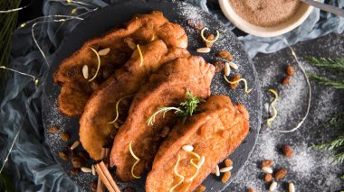 Traditional Christmas Rabanadas with lemon zest, raisins, pine nuts and cinnamon. Spanish Torrijas or french toasts close up on the countertop