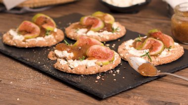Kanepe veya crostini ile krem peynir ve incir ile tahıllı crispread jam kayrak bir gemide. Lezzetli meze bir aperatif ideal.