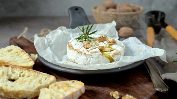 Brie类型的奶酪 Camembert奶酪 新鲜切碎的布里奶酪放在有坚果 蜂蜜和叶子的木制托盘上 意大利语 法语奶酪 — 图库视频影像