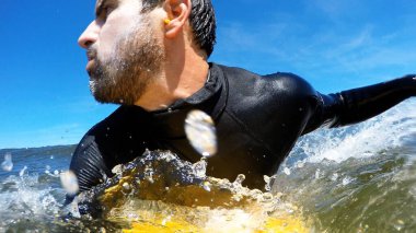 Genç adam dalgalarda sörf yapmaktan hoşlanıyor..