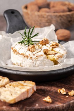 Brie peyniri. Camembert peyniri. Tahta tepside taze dilimlenmiş peynir, fındık, bal ve yapraklarla. İtalyan, Fransız peyniri.