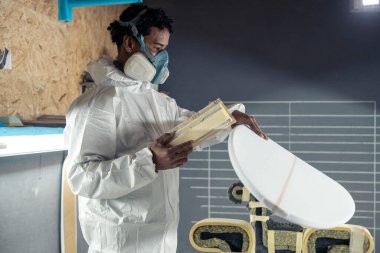 Sörf tahtası imalatı, sörf tahtası ayrıntıları üzerinde çalışan şekillendirici. Endüstriyel imalat, nitelikli profesyonel, mesleki ve istihdam kavramı.