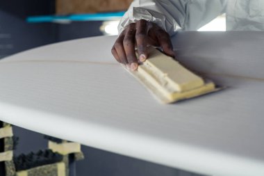 Sörf tahtası imalatı, sörf tahtası ayrıntıları üzerinde çalışan şekillendirici. Endüstriyel imalat, nitelikli profesyonel, mesleki ve istihdam kavramı.