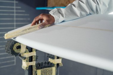 Sörf tahtası imalatı, sörf tahtası ayrıntıları üzerinde çalışan şekillendirici. Endüstriyel imalat, nitelikli profesyonel, mesleki ve istihdam kavramı.